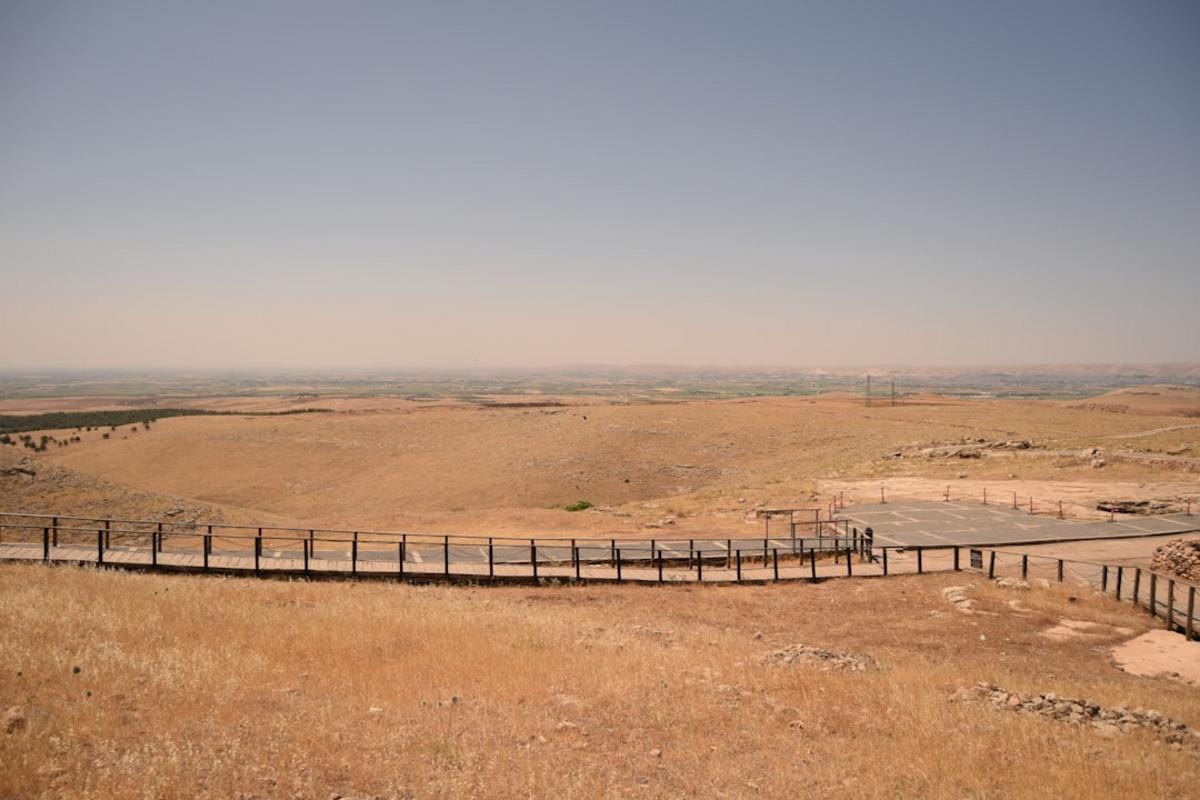 A panoramic view of Göbeklitepe's ancient stone circles under a clear sky, showcasing the scale and mystery of the site.