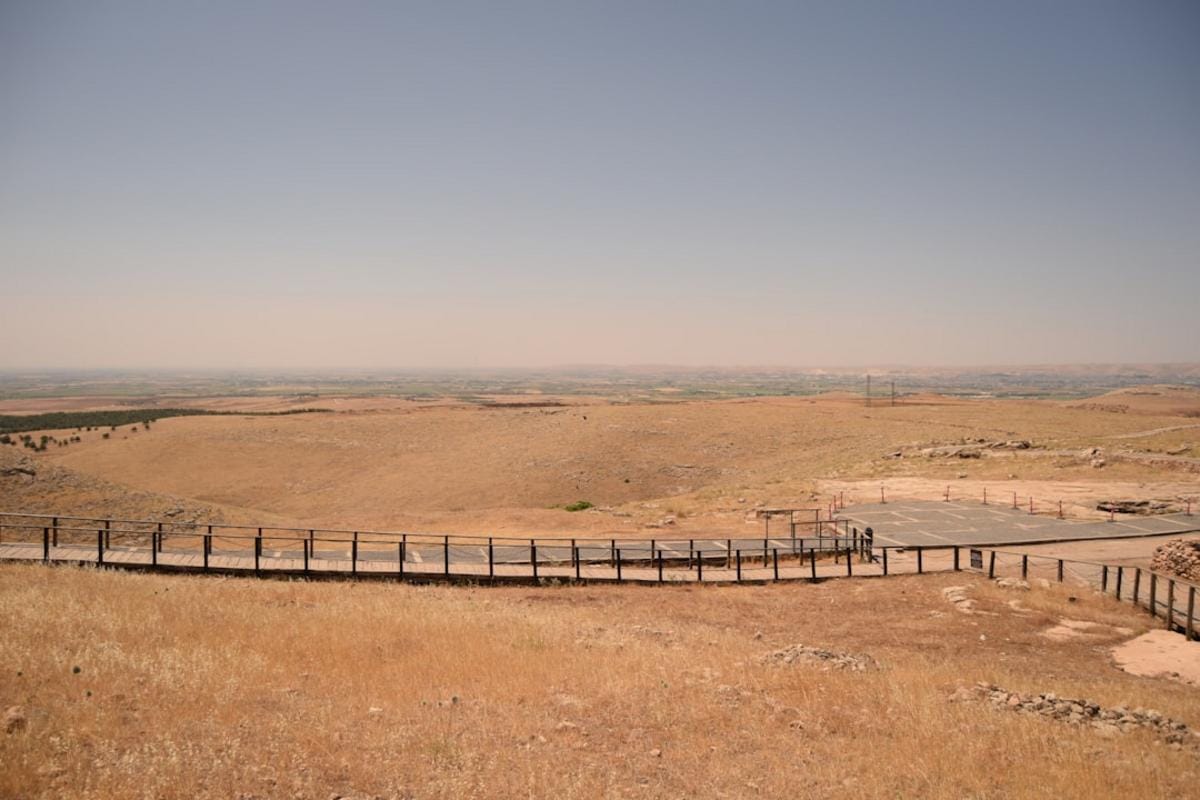 A panoramic view of Göbeklitepe showing its circular stone pillars and ancient structures under a clear sky