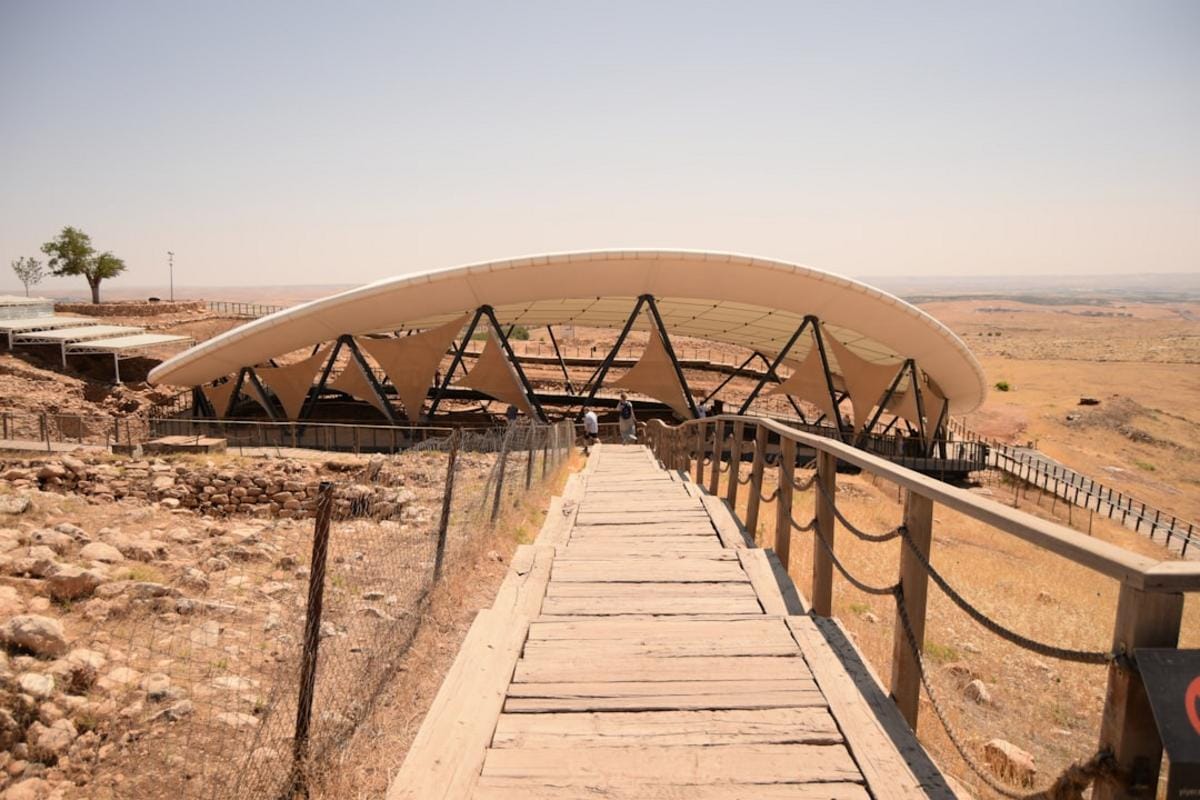 A panoramic view of the ancient stone circles of Göbeklitepe, with detailed carvings and towering T-shaped pillars, illuminated under a clear sky.